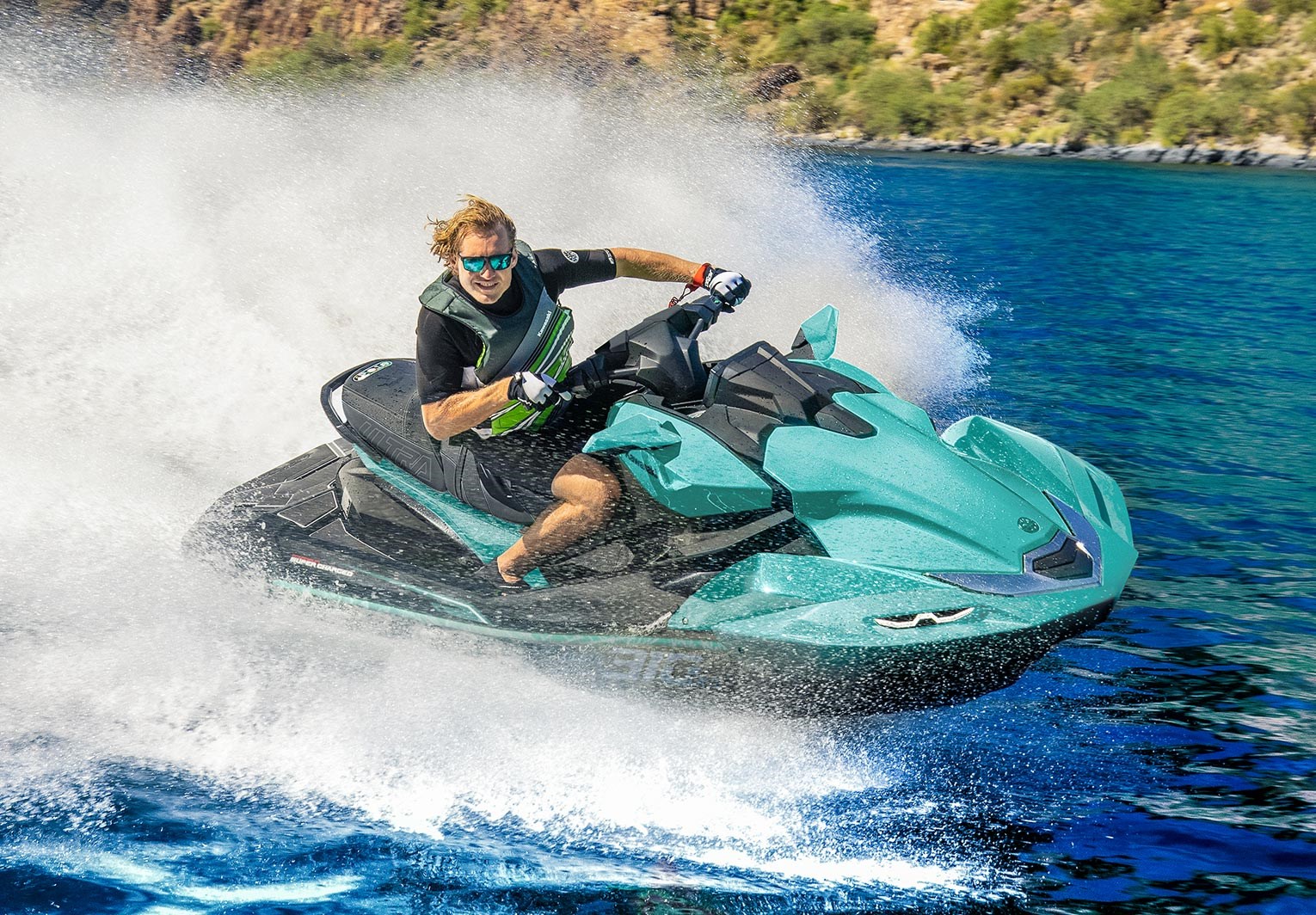 Moto de agua Kawasaki Ultra a alta velocidad, agua turquesa y costa rocosa